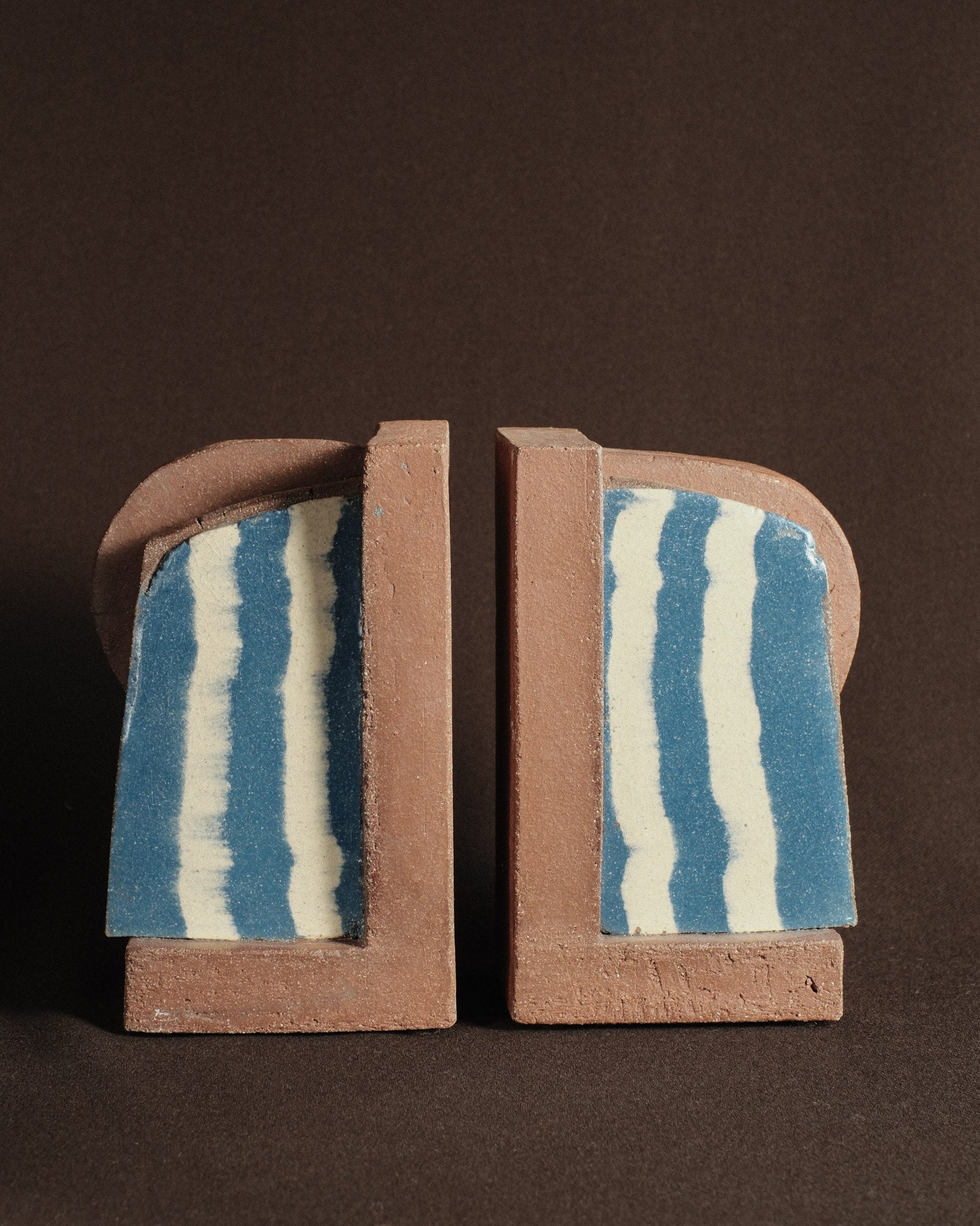 Pair of Shane Gabier ceramic bookends in pigmented clay with banded inlay, shown as two sculptural forms.