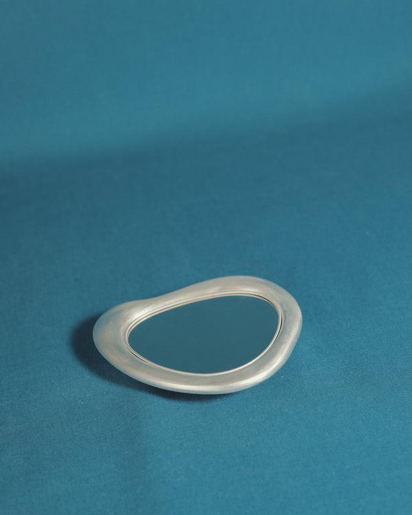 Christian+Jade Mirror silver-plated metal and polished stainless steel compact handheld object capturing reflection and trace of use.