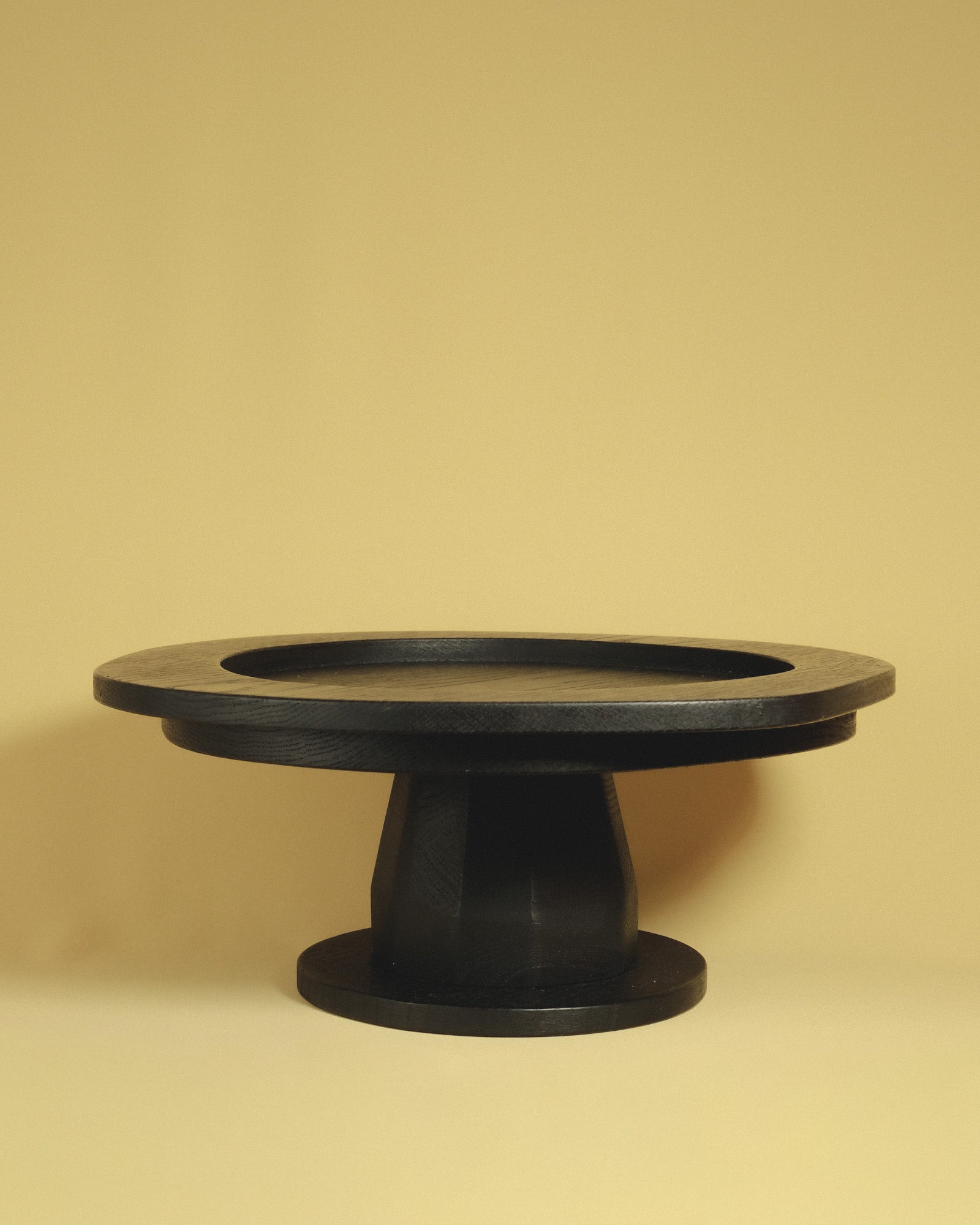 Christian+Jade Pedestal carved from oxidised oak with sharp geometry and darkened surface elevating and balancing the table.