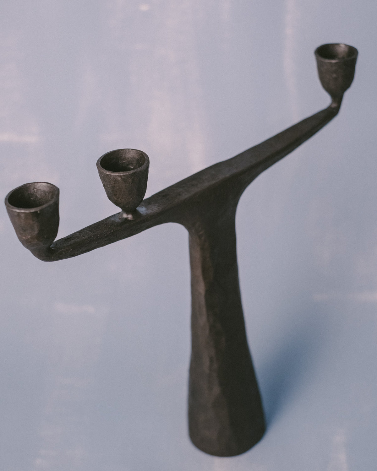 Forged steel candle holder by Agnieszka Owsiany, curved twin arms, angled view