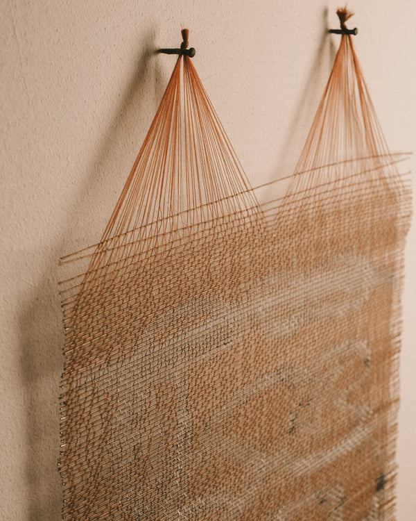 Fringed edge of woven wall piece, brown thread texture