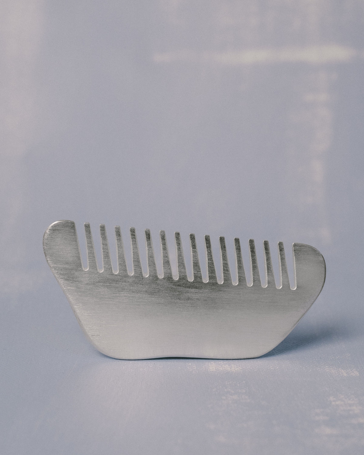 Christian+Jade Comb, shaped from silver-plated metal, side profile showing polished surface and comfortable hand-held form