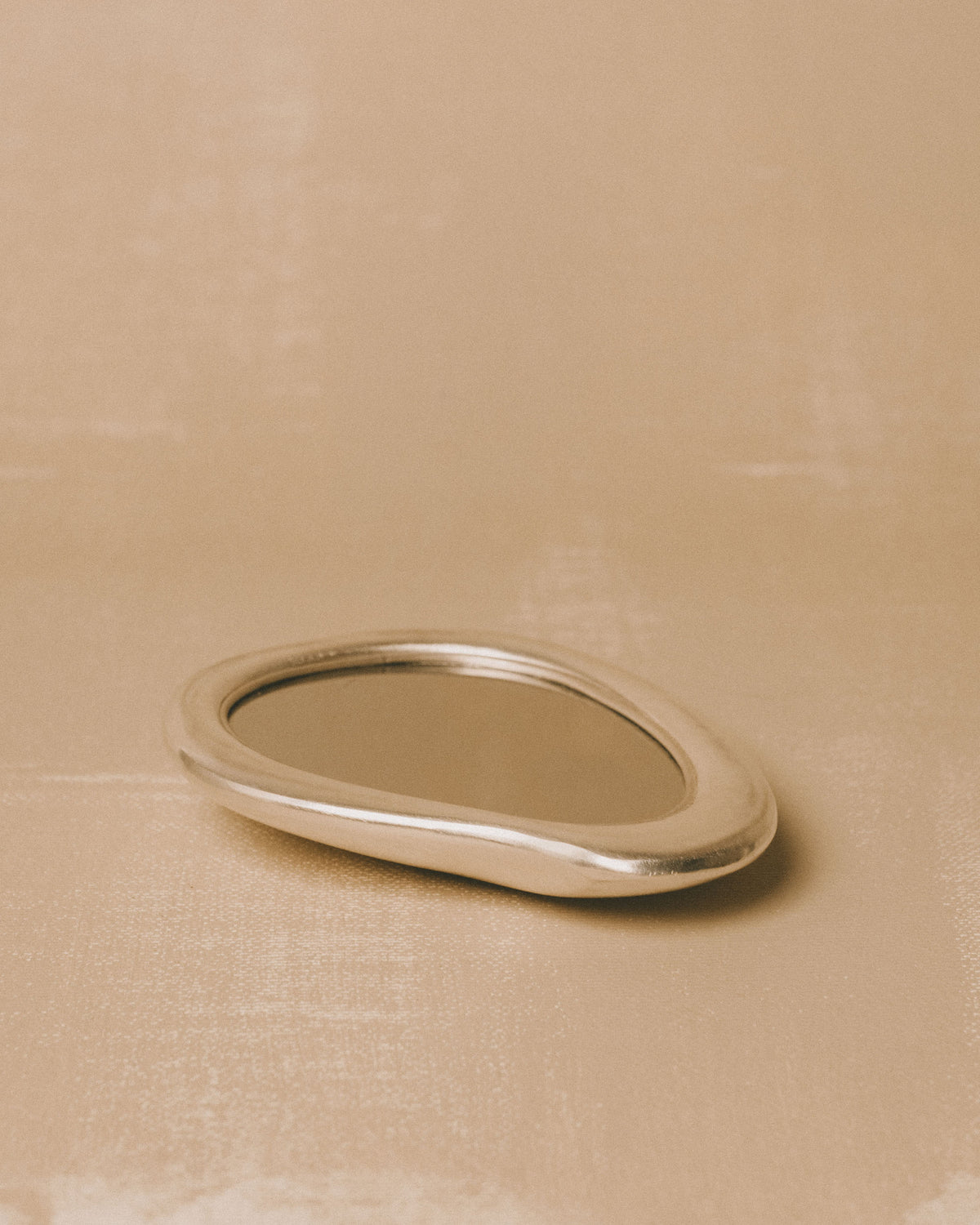Angled view of Christian+Jade Mirror, silver-plated metal with polished reflective surface