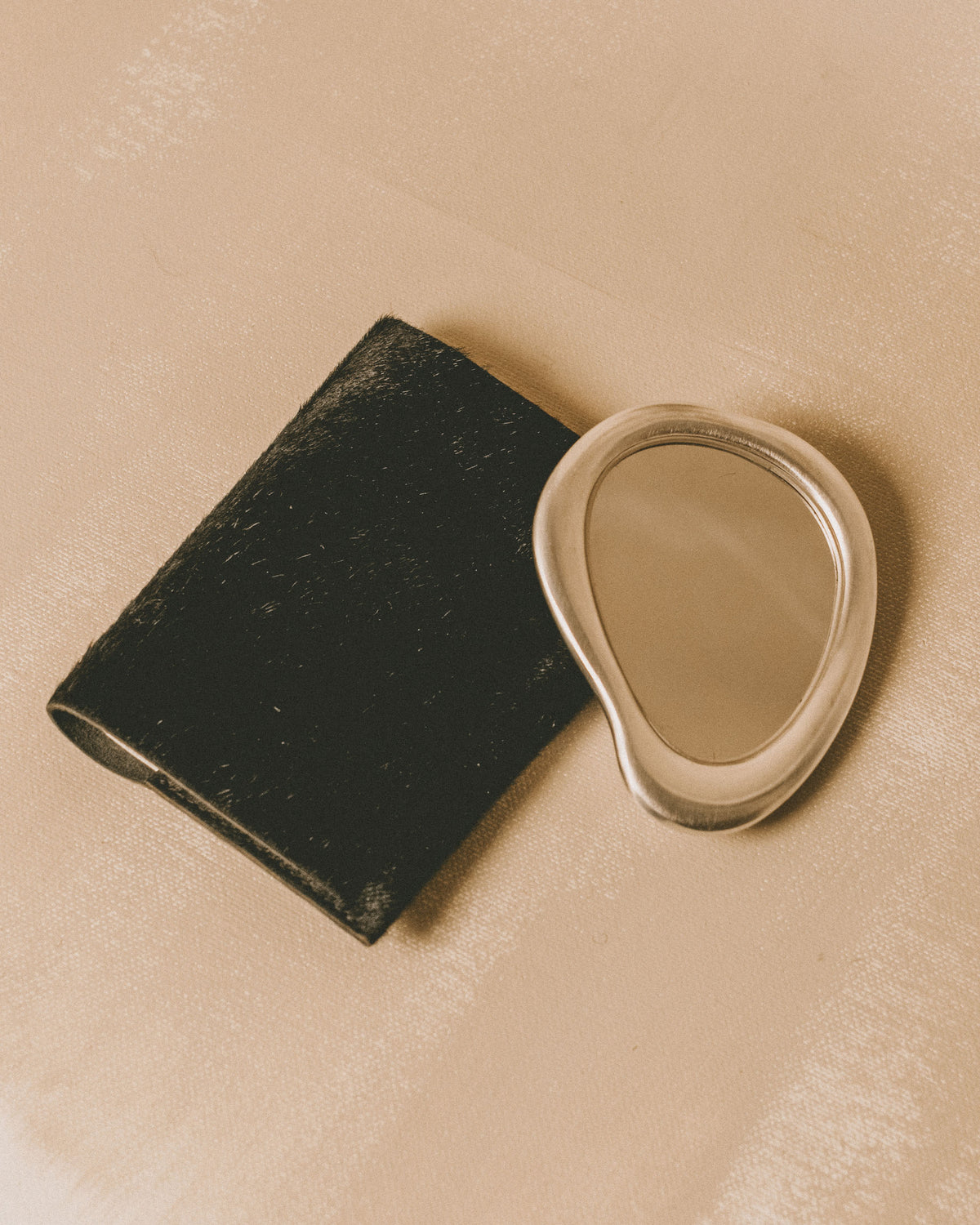 Christian+Jade Mirror shown with black protective pouch, silver-plated compact object