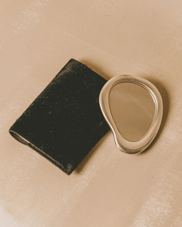 Christian+Jade Mirror shown with black protective pouch, silver-plated compact object