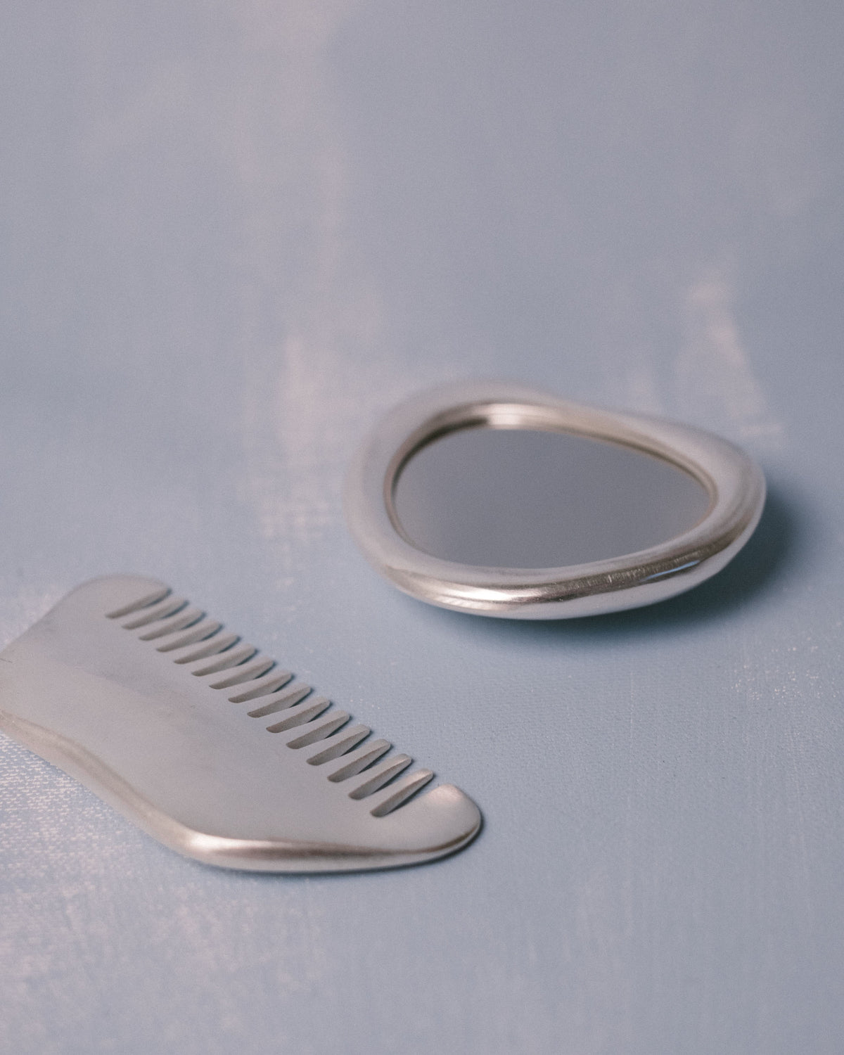 Silver-plated Vanity Set by Christian+Jade, mirror and comb in polished metal, angled view
