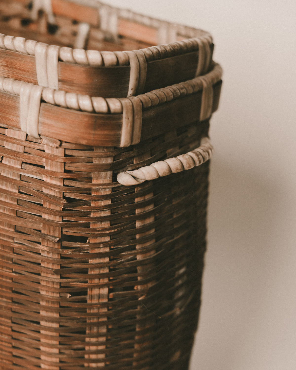 Tall handwoven bamboo basket, wooden base, side profile