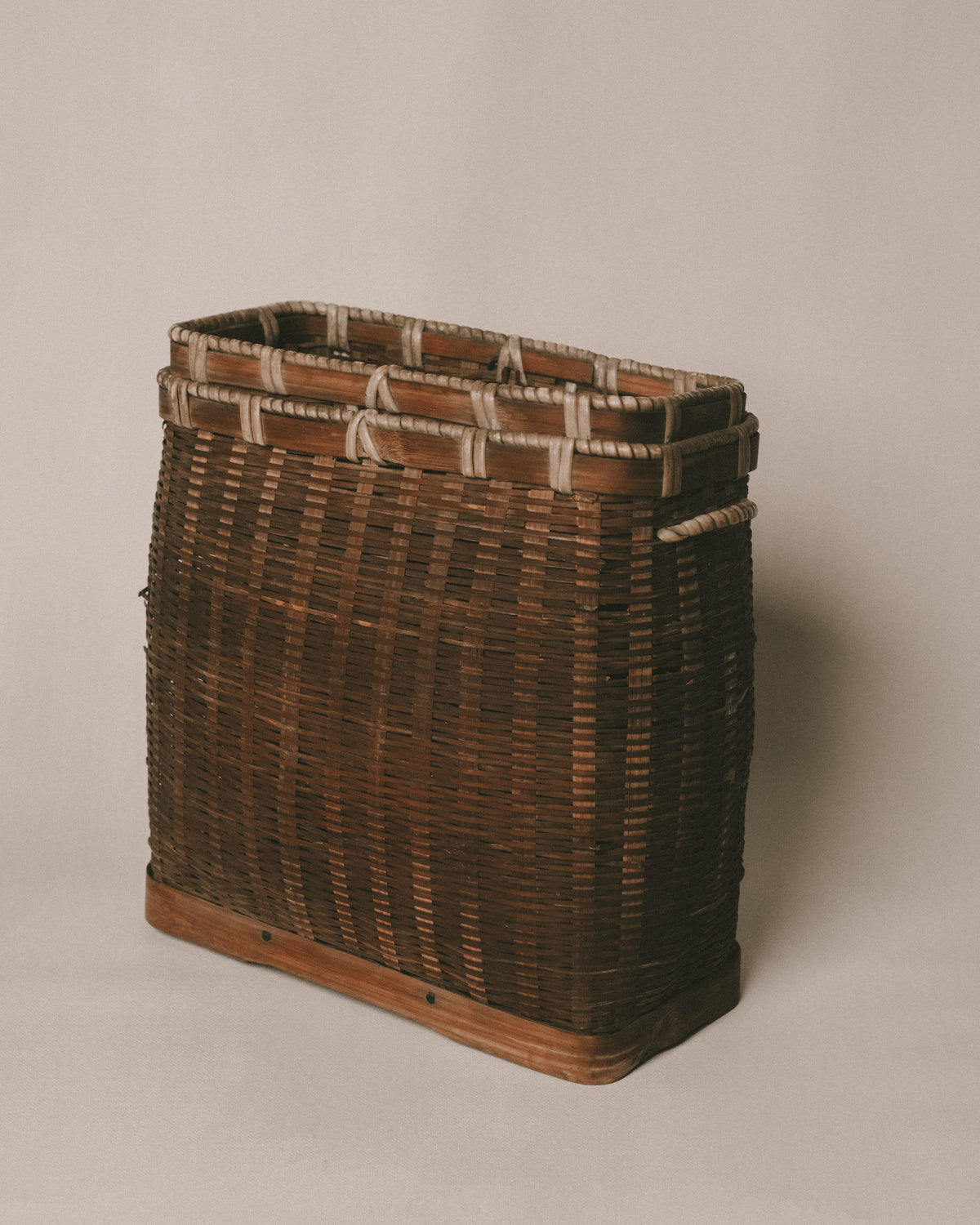 Handwoven bamboo basket with wooden base, rope handles, front view
