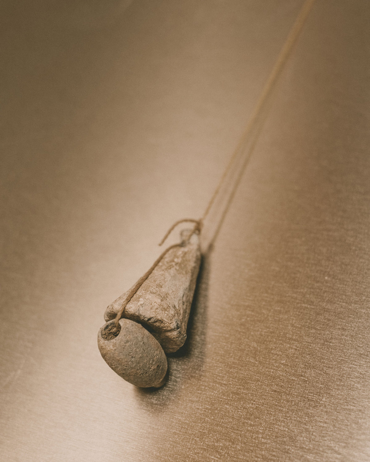 Close-up of single vintage lead loom weight, part of Louie Isaaman-Jones Book Stand