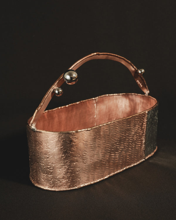 Layered copper and brass surface of Container 1, angled view