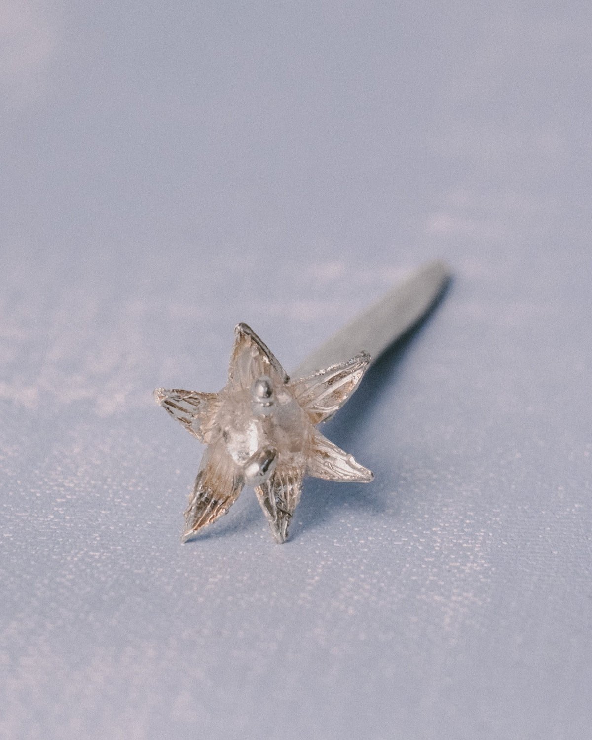 Vertical detail of Yeodong Yun Dessert Pick, handmade sculptural silver flower celebrating nature's cycle